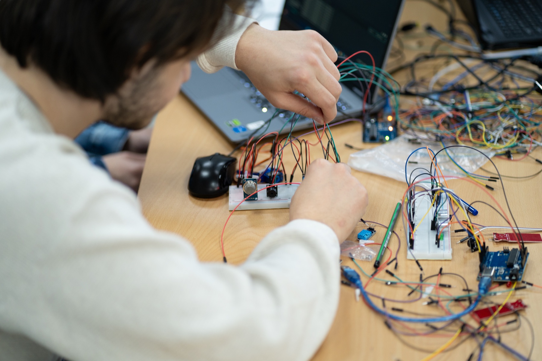 A student wiring sensors on a breadboard connected to an Arduino