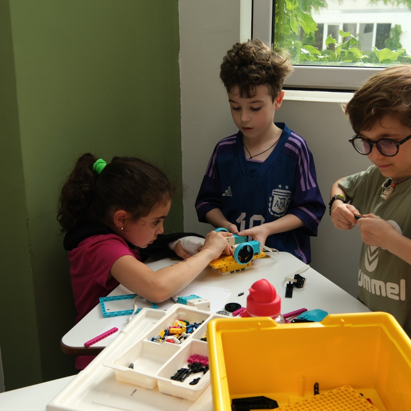 Children building a LEGO robot together at Clevermind Academy, with LEGO parts and a kit on the table